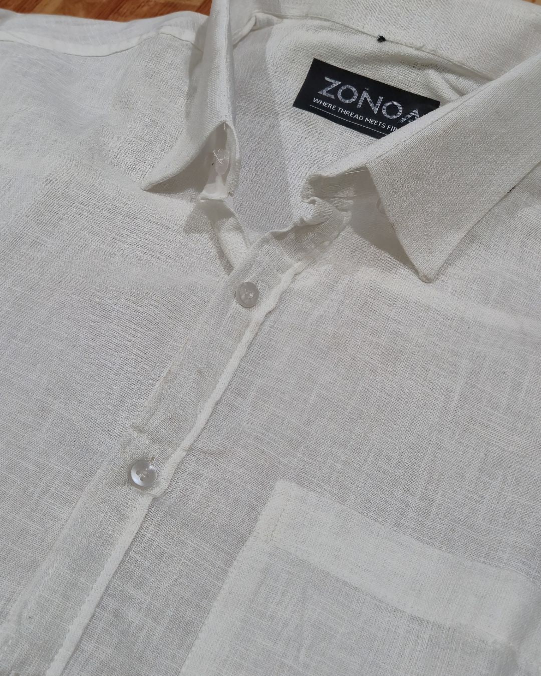 Close-up of a white linen button-up shirt, showing the collar, fabric texture, and brand label.