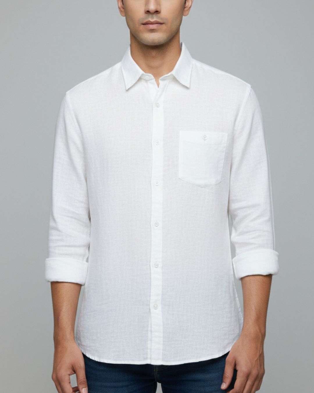 A man wearing a white long-sleeve linen shirt with a chest pocket, shown from the chin down against a solid gray background.
